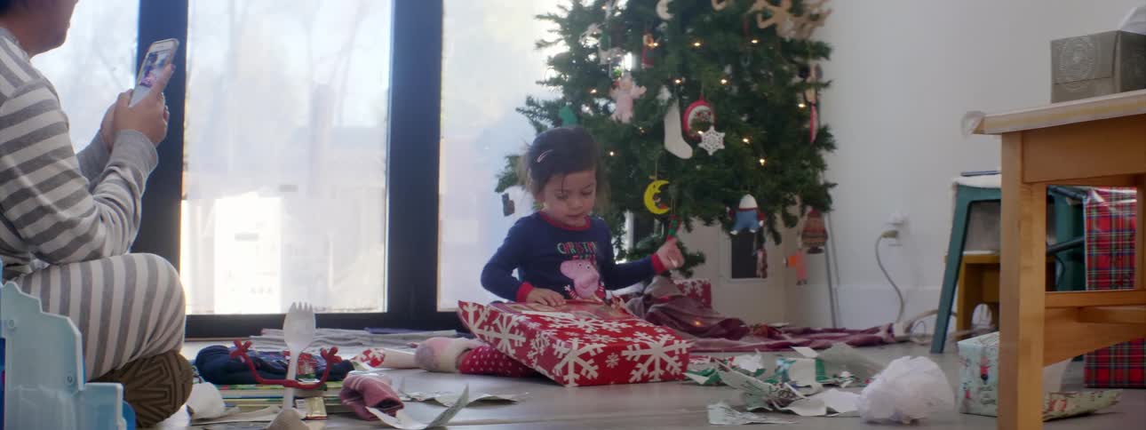 A father records his daughter opening a christmas present on his phone