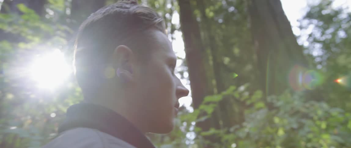 A man is hiking out in the woods on a sunny day