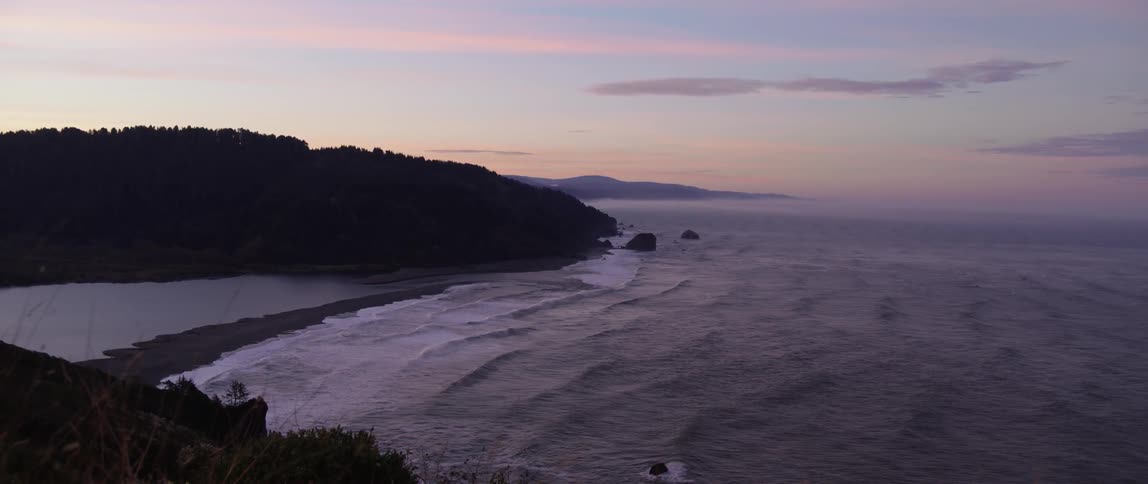 Gentle ocean waves washing onto a beach after sunset