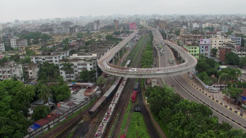 People ride atop a train as it travels under an overpass in a dilapidated metropolis