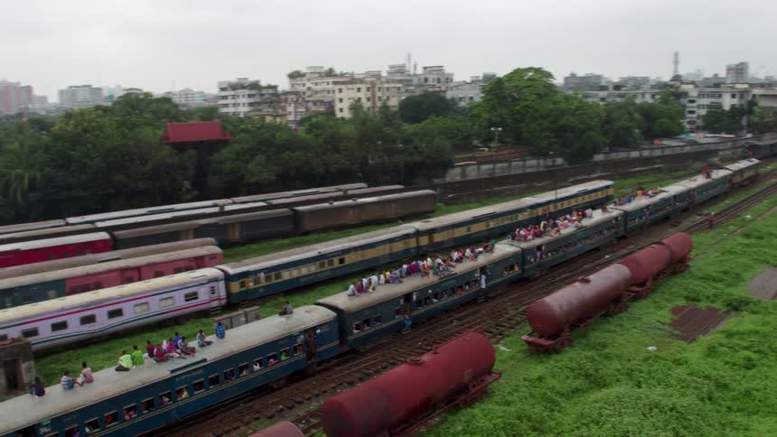 An aerial view of people in a train and on top of a train heading in to a city