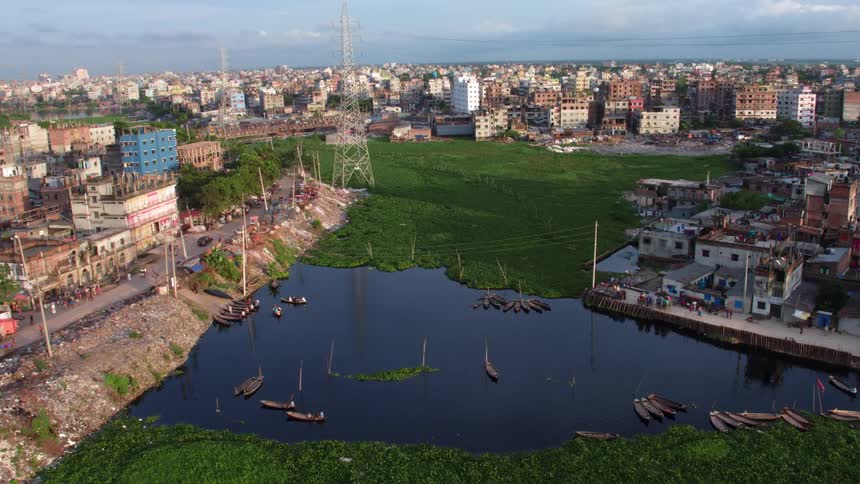 An aerial view of a city in a primitive area with people walking down the streets and people rowing boats in the water