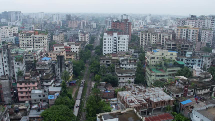 Aerial view of a train driving through the buildings of a city