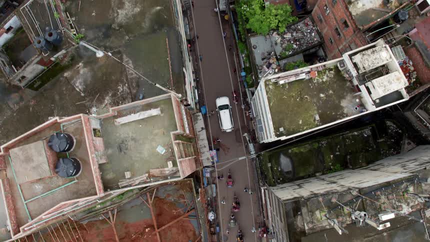 Birds eye view of cars driving and people walking in a beaten up neighborhood