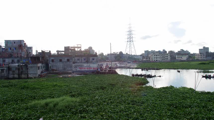 Men row boats along river toward small town under very cloudy sky