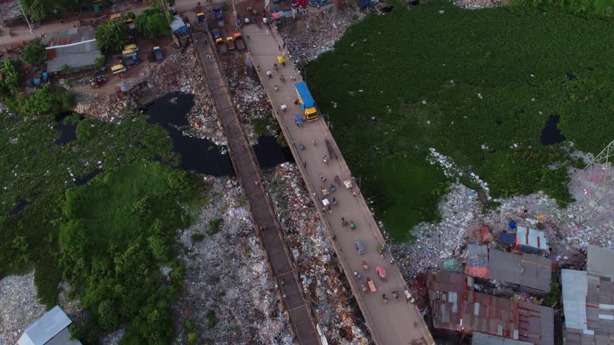 Aerial view of people driving on a road in a landfill next to slums