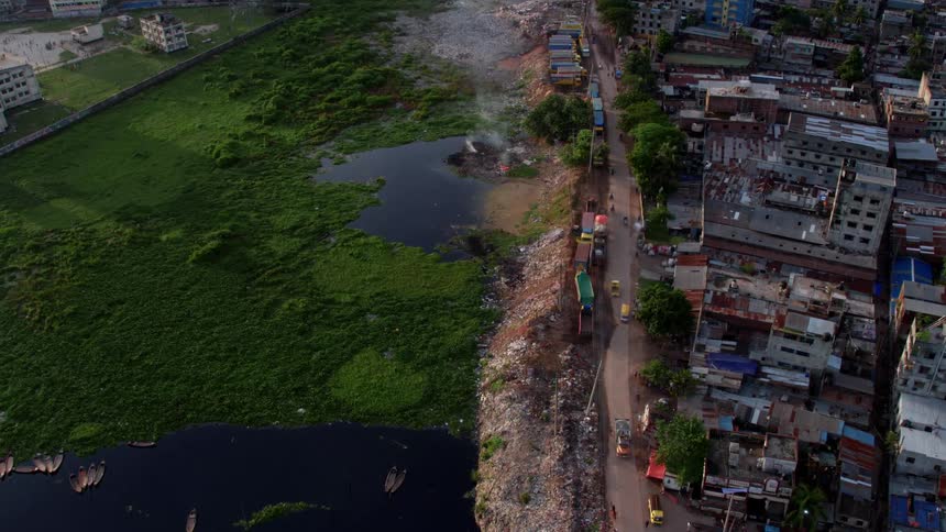 A large urban area has a large number of dilapidated buildings next to a swampy area filled with trash