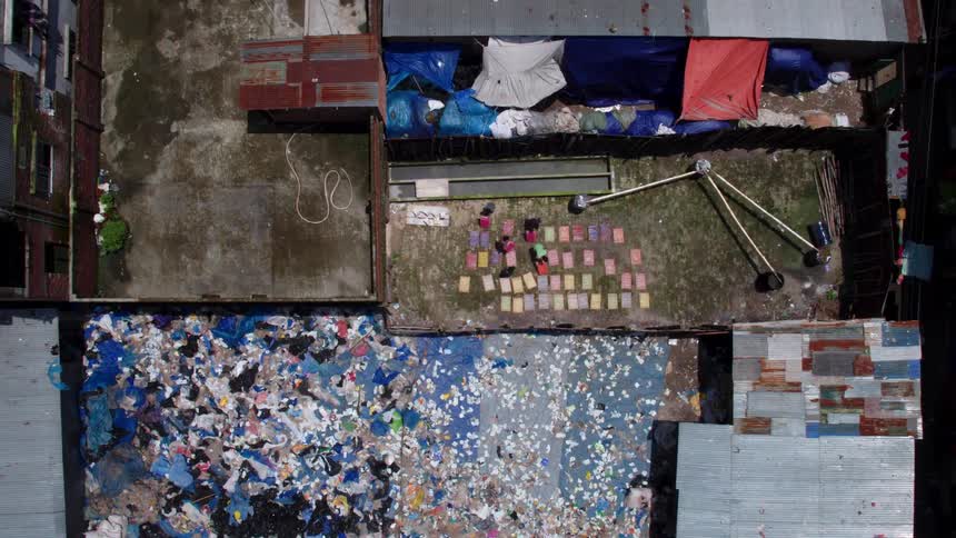 Aerial view of people digging through garbage in a primitive village