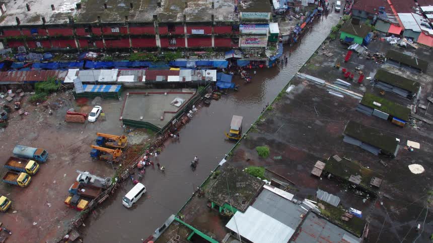 Pedestrians and vehicles move through flooded street