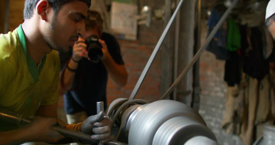A man taking photos of two men sculpting
