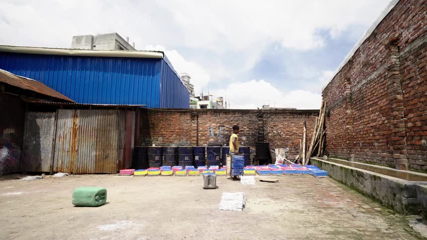 A teenage boy in a factory in a village carries pallets outdoors