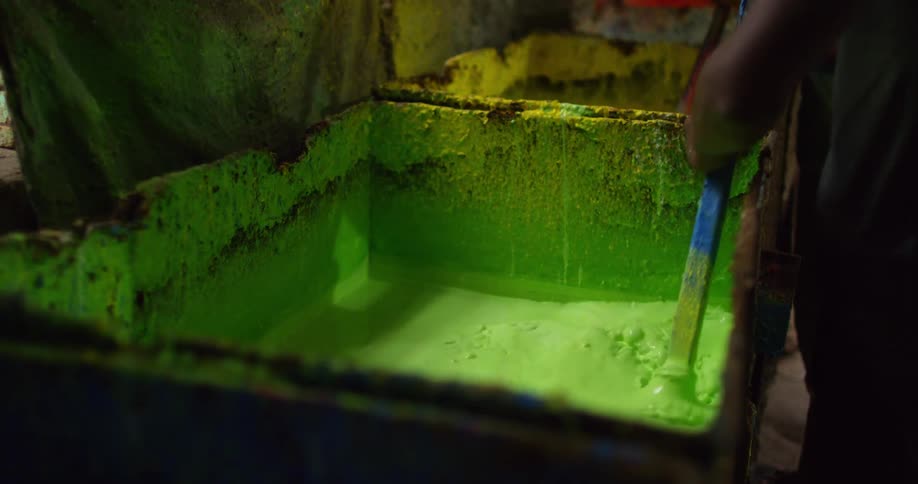 Children stirring dye for balloons in bins