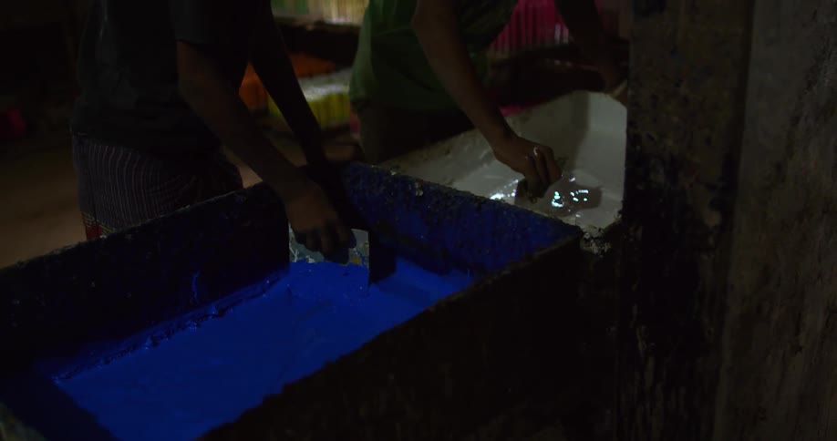 Two teenage boys stir paint inside an old building