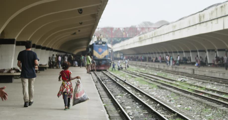 A young girl carries a bag running towards a train at a train station