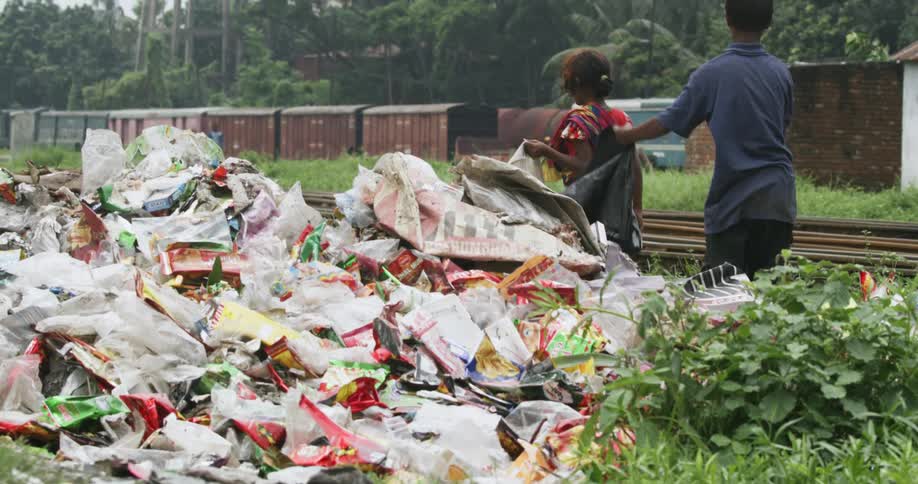 Two children pick up trash by the railroad tracks