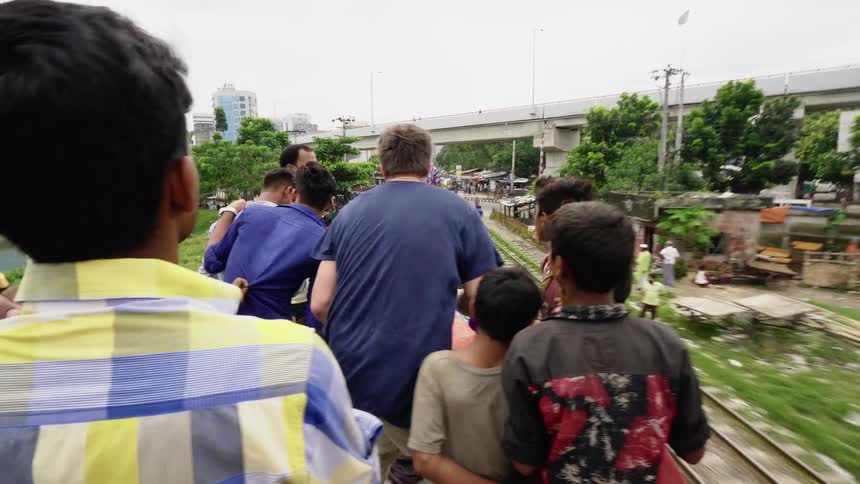 Photographer talks to boys and teenagers standing on the roof of a moving train