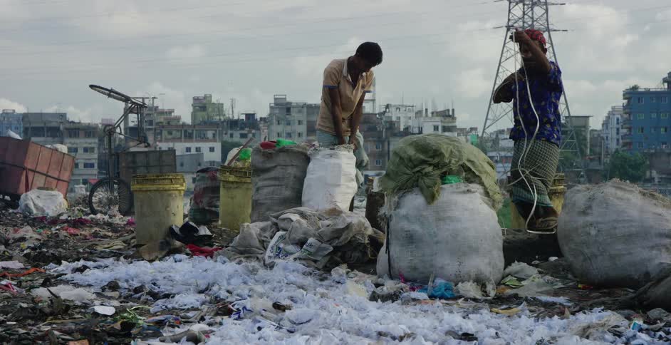Two man fill bags with garbage for recycling in a third world country