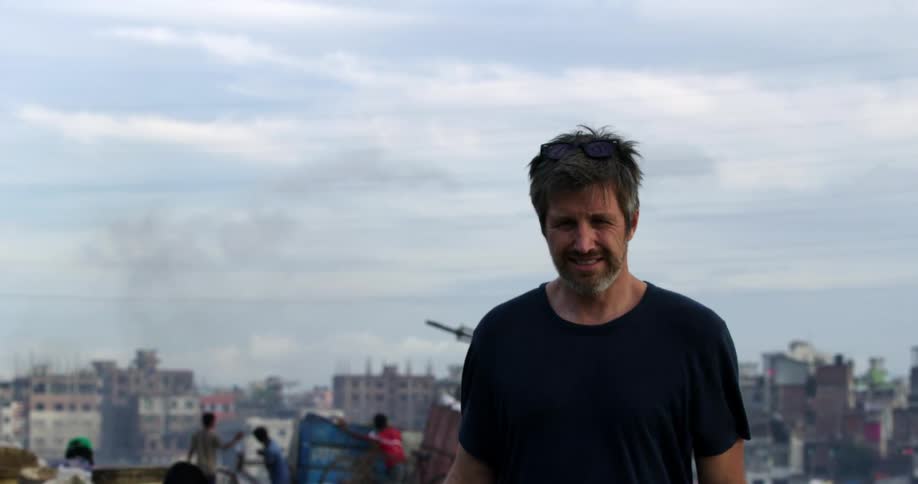 Photographer carrying a camera walks on a landfill in a third world country