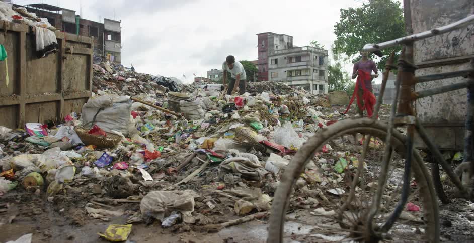 Group of people collecting garbage on a landfill next to a slum