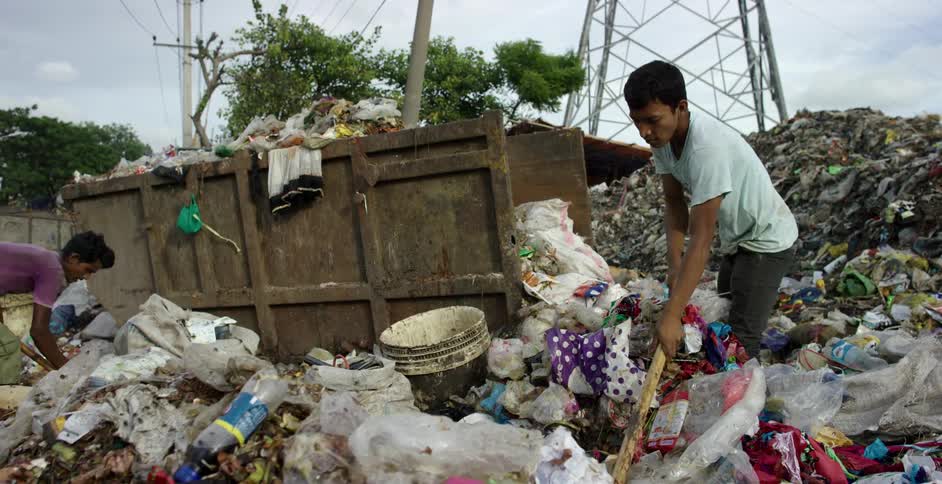 Two young men going through rubbish in a landfill