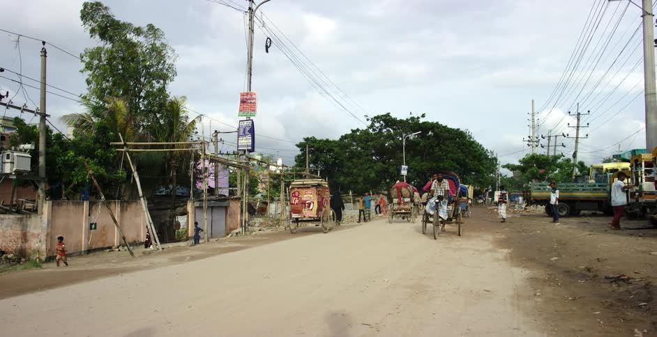 Men carry passengers along a dirt road in cycle rickshaws during the day