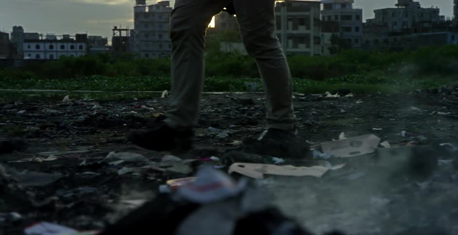 A man walks through burning garbage on the outskirts of a third world city