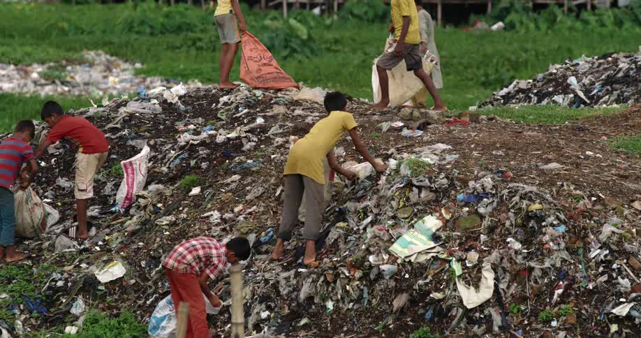 A group of children picking up trash on a hill
