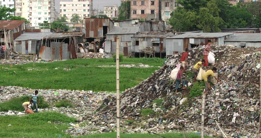Group of children climb a pile of garbage on a landfill near a slum
