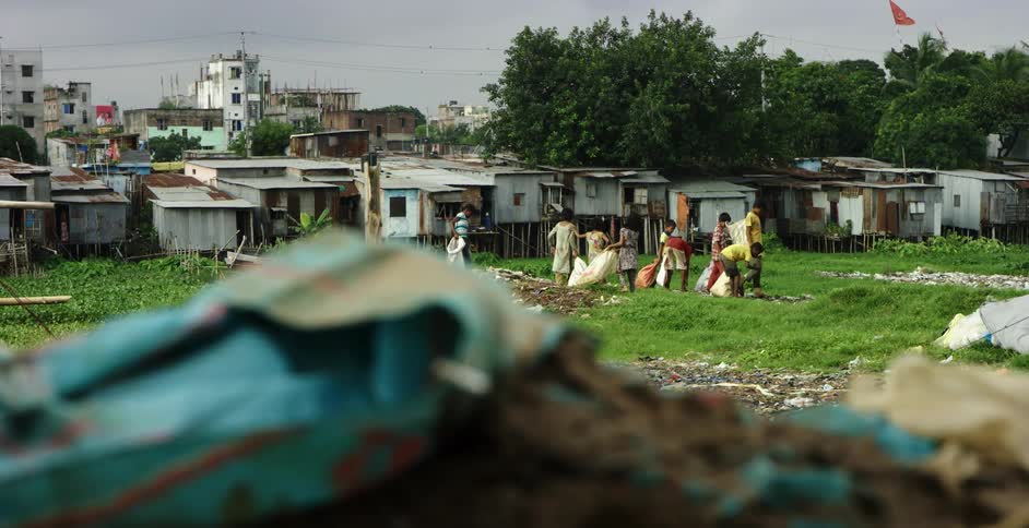 People picking up trash in a shack city