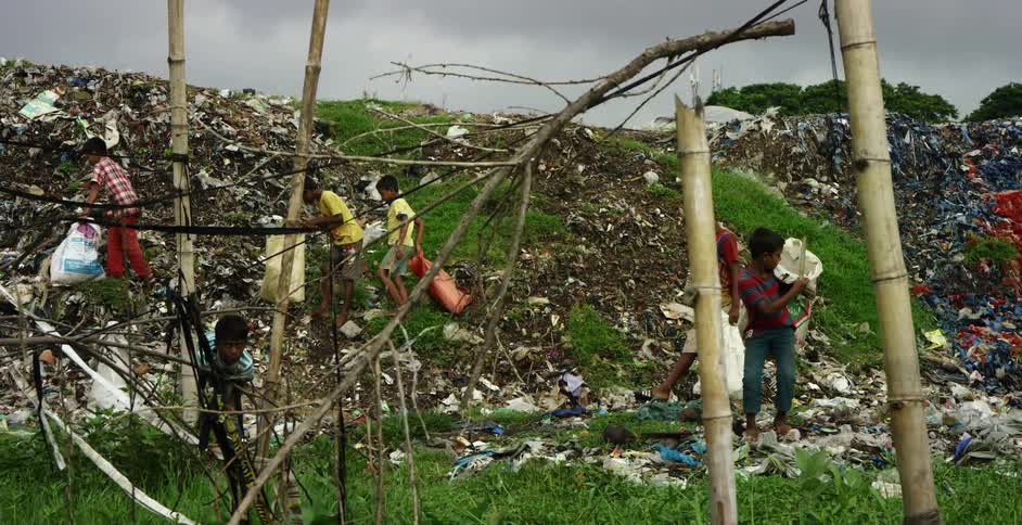 Children in a primitive area dig through garbage at a dump