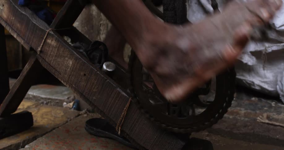 A person with incredibly dirty feet pedals on a makeshift stationary bicycle
