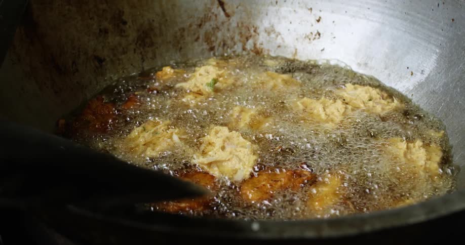 A person drop dough in to boiling grease as they cook