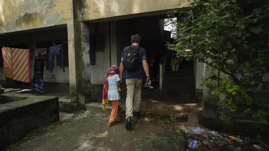 A photographer and a girl walk into a building holding hands