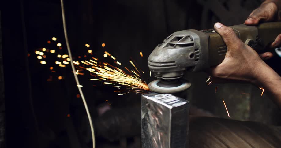 Sparks fly as a man uses a tool on steel