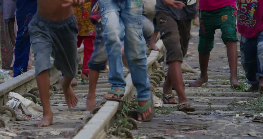 People walking on train tracks with stones and grass in the background