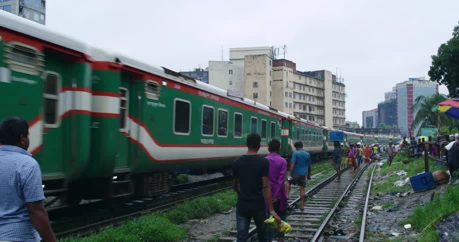 People walk on railroad next to moving passenger train