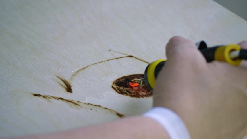 A man burns an image on to a piece of wood