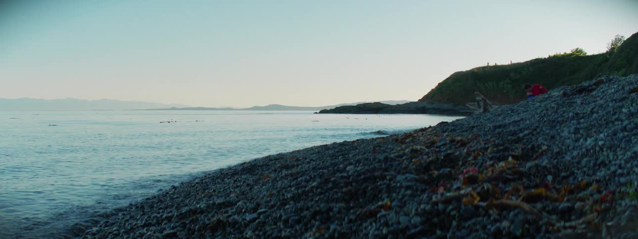 A person sitting on the rocky shore
