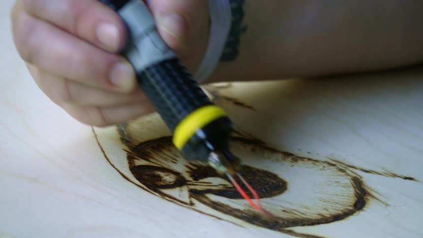 A person using a tool to burn an image onto wood