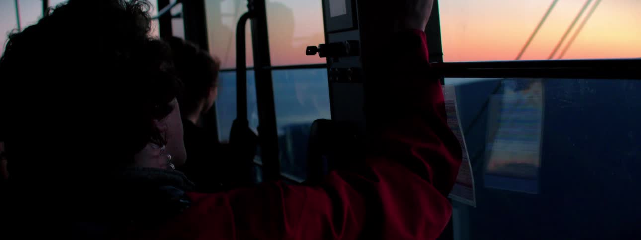 Person riding in cable car down mountainside at sunset