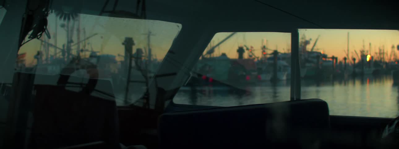 A boat docked at a crowded port at sunset
