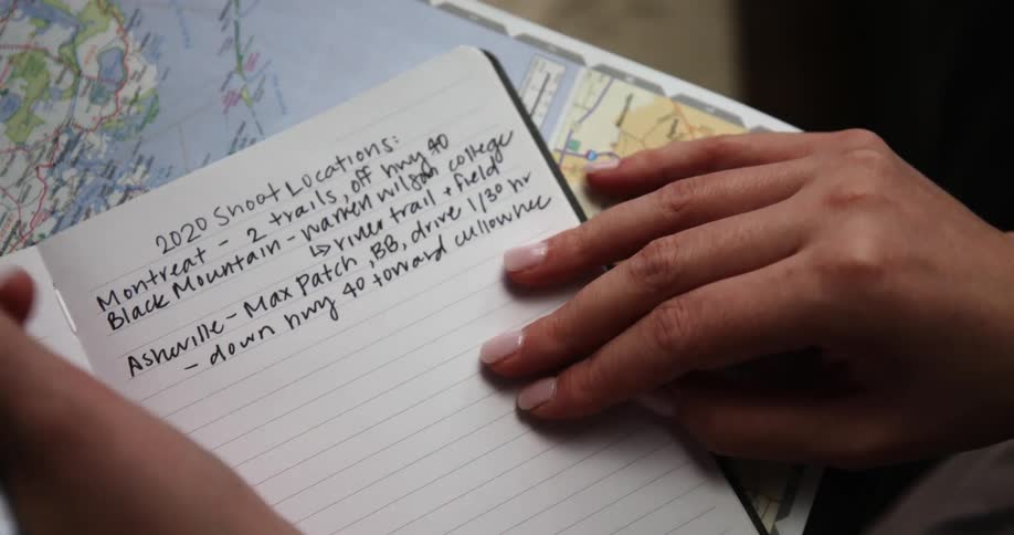 Womans hand writes in a notebook with a pen on a map