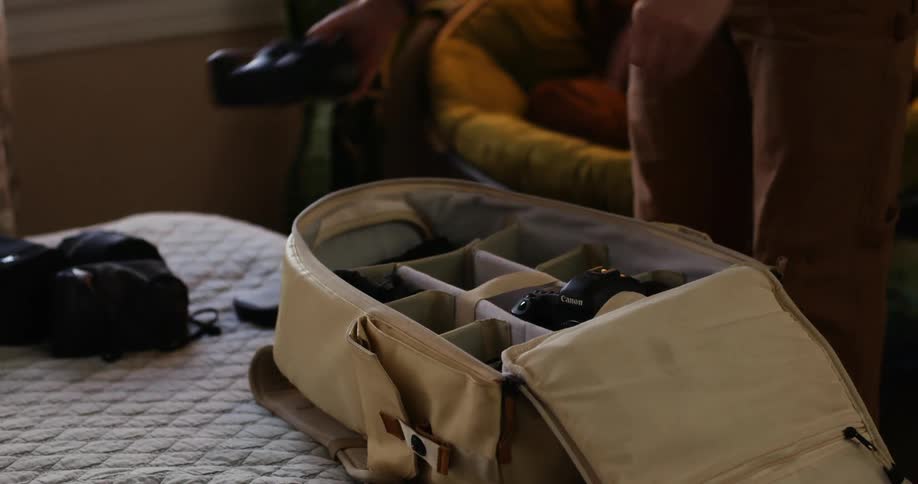 A woman at home packs a bag with her photography equipment