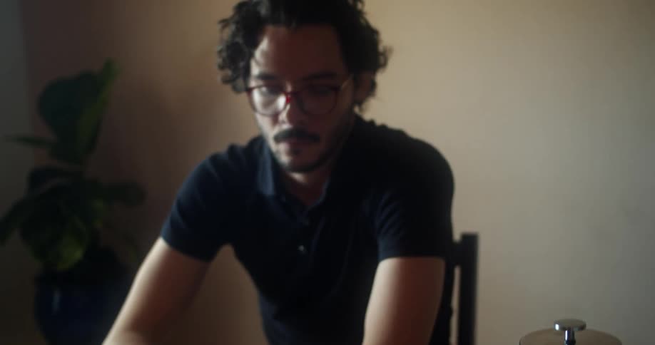 A man sits indoors at a table while reading a book