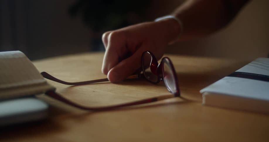 Person places glasses on table next to books