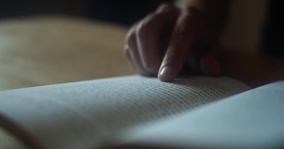Man reading a book follows the text on the page with his finger
