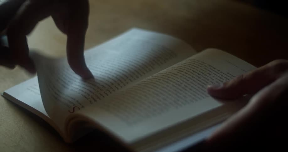 A man flips through pages in a book at a table