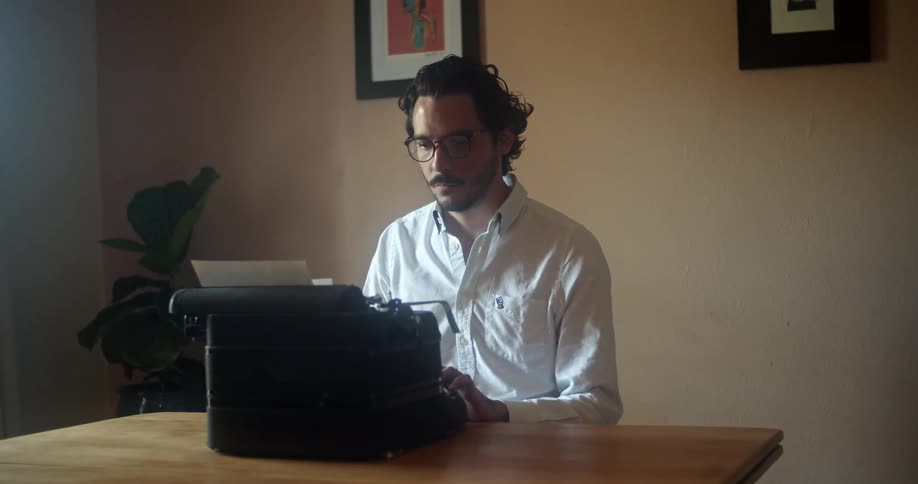 A man in an office types on a vintage typewriter