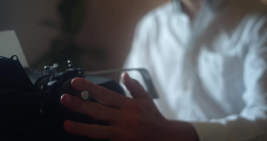 A man in a white button up shirt typing on a typewriter