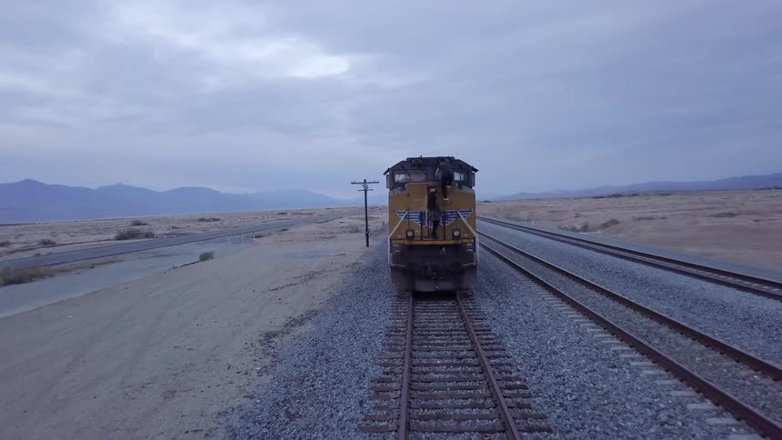 A man and a woman climbing a train with the sky and clouds in the background
